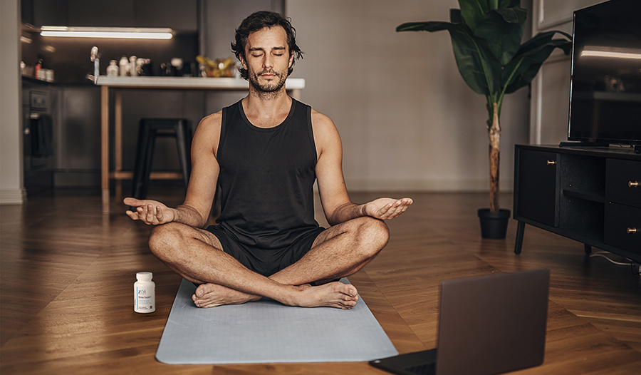 Man meditating on yoga mat at home