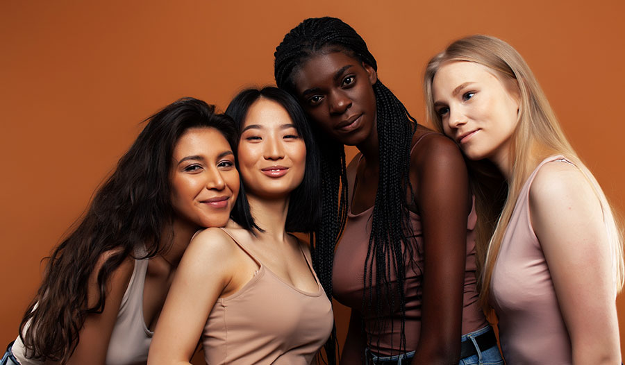 group of four women with healthy and full hair smiling at the camera