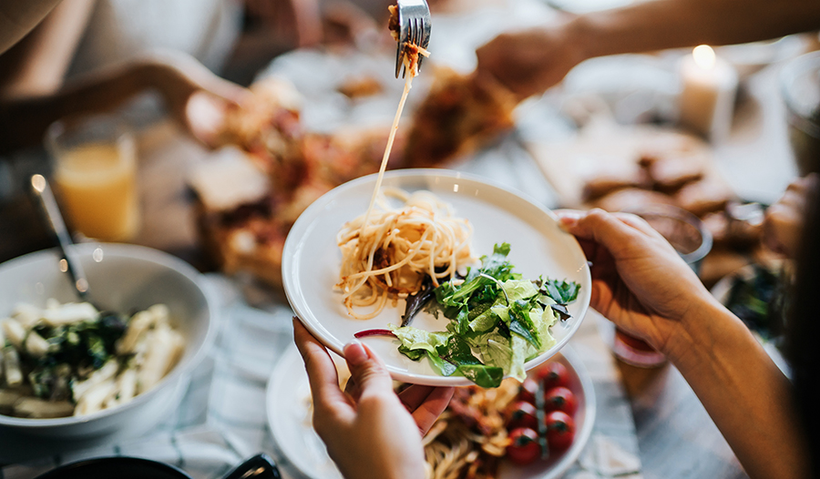 Friends sharing a meal of spaghetti and salad