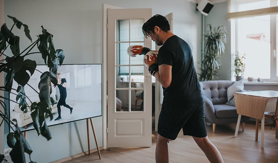 Asian man wearing boxing gloves does boxing workout video at home