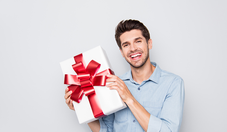 cheerful man holding up wrapped holiday gift