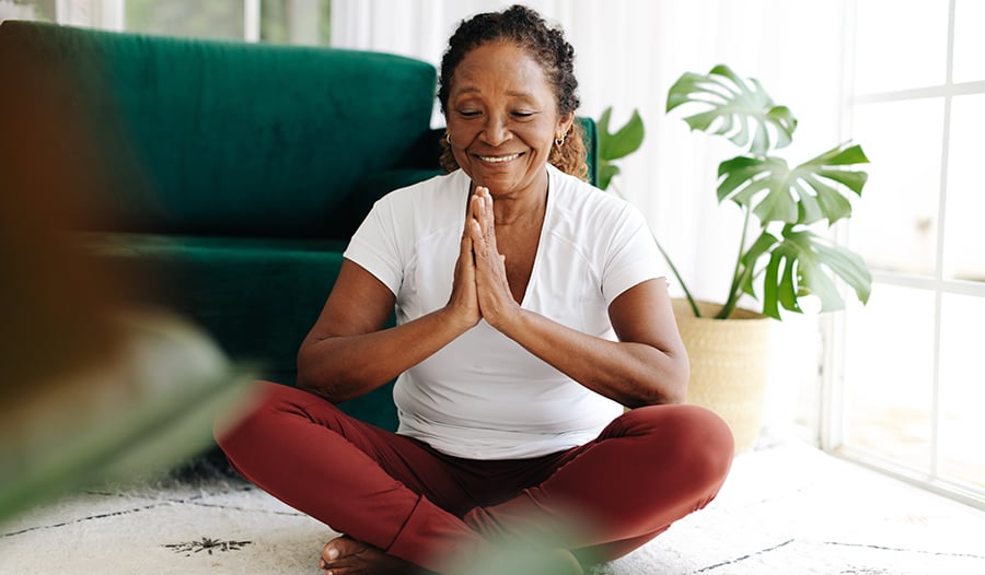 Woman meditating and smiling sitting on floor at home
