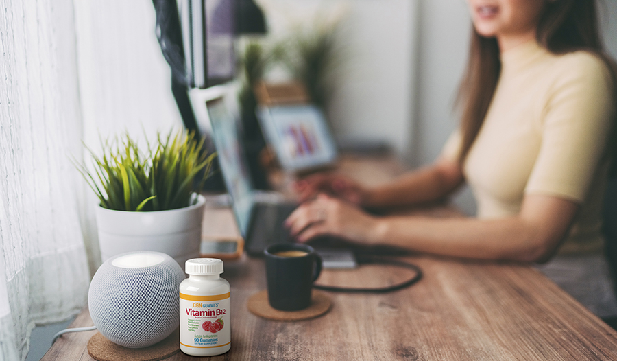 Woman working on laptop at desk with coffee and vitamin B12