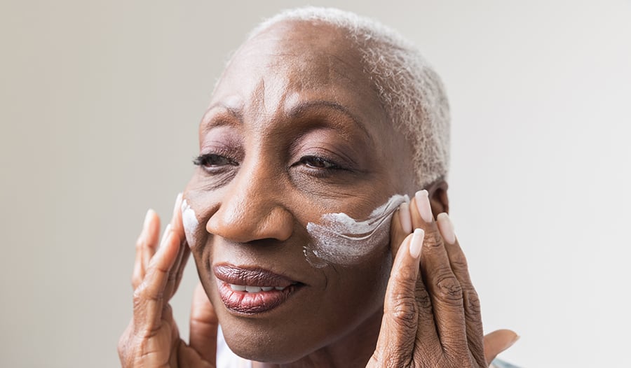 Mature woman applying moisturizing cream to face
