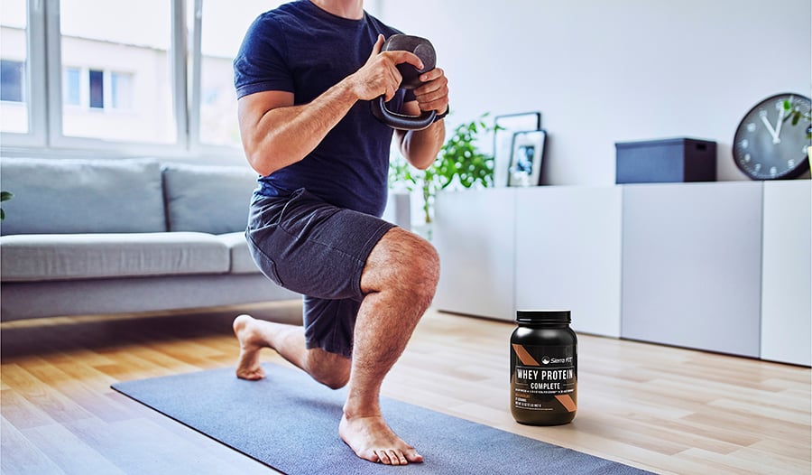 Male working out at home doing lunges with kettlebell