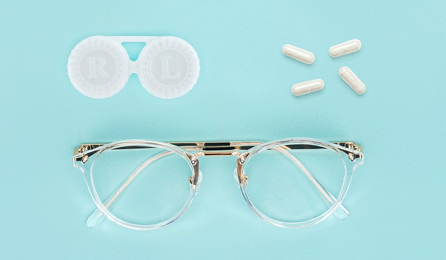 Eye glasses, contacts case, and vision supplements on blue background