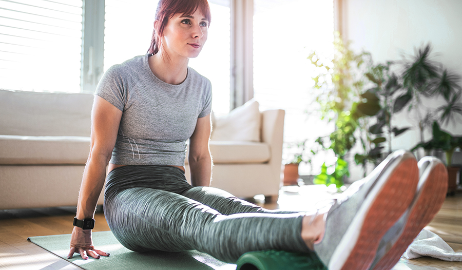 Young active woman using foam roller at home