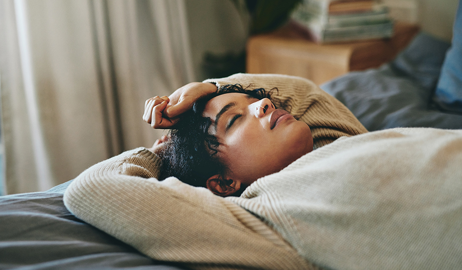 Young woman lying on her bed with her eyes closed