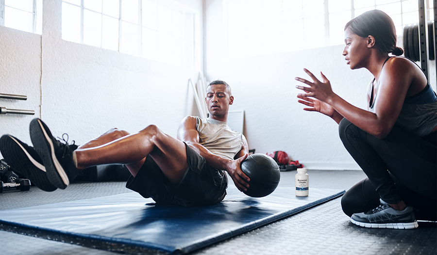 Trainer coaching athlete at gym with magnesium supplement in background