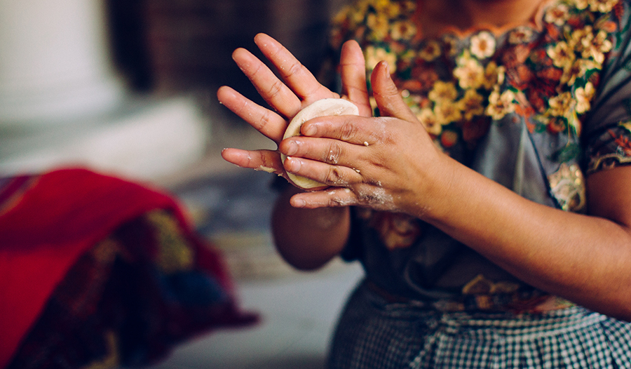 Woman rolling dough in hands making homemade tortillas 