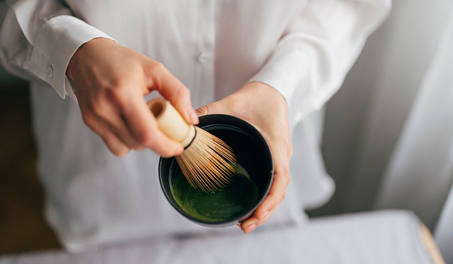 Male making matcha in bowl with whisk