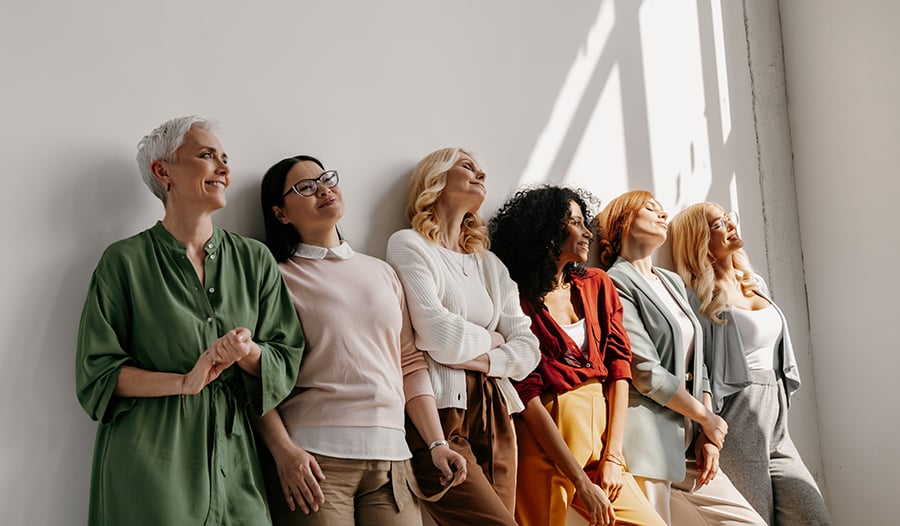 Group of women smiling standing against a wall