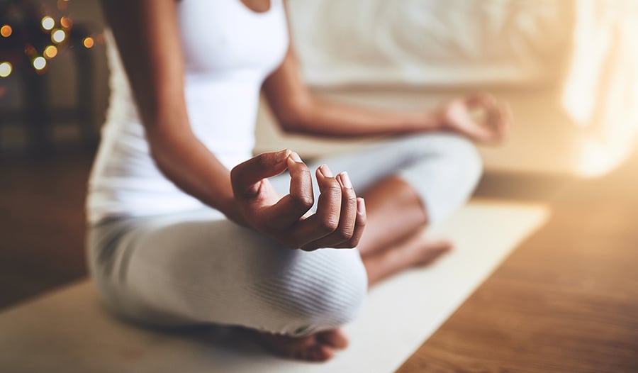 Woman practicing yoga meditation on mat at home