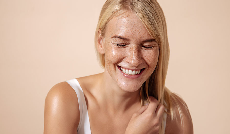 woman with blond hair and freckles smiling with her eyes closed