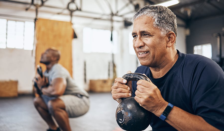 Mature males working out with kettlebells in gym