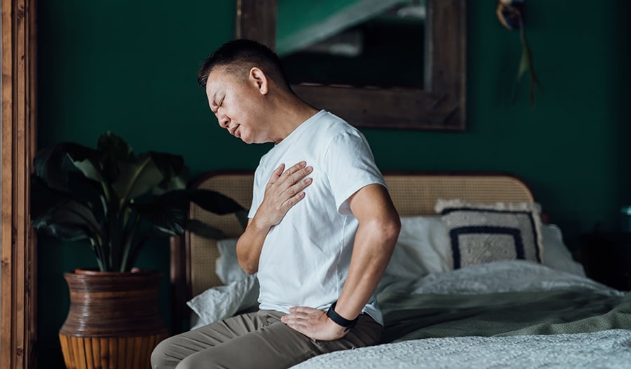 Male man holding chest sitting on bed