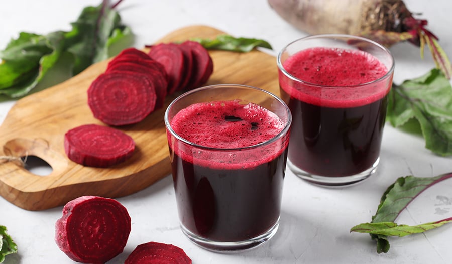 Beet juice in glasses and beets on wooden chopping board