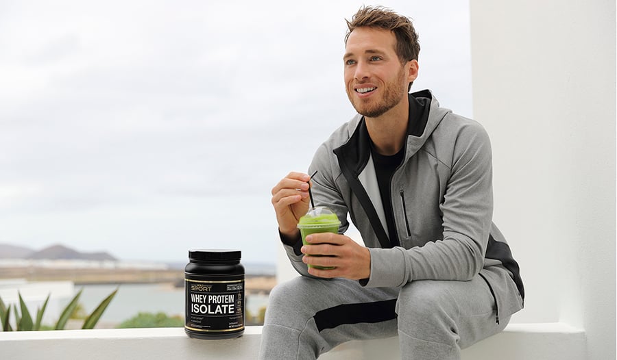 Athletic male drinking green smoothie outside