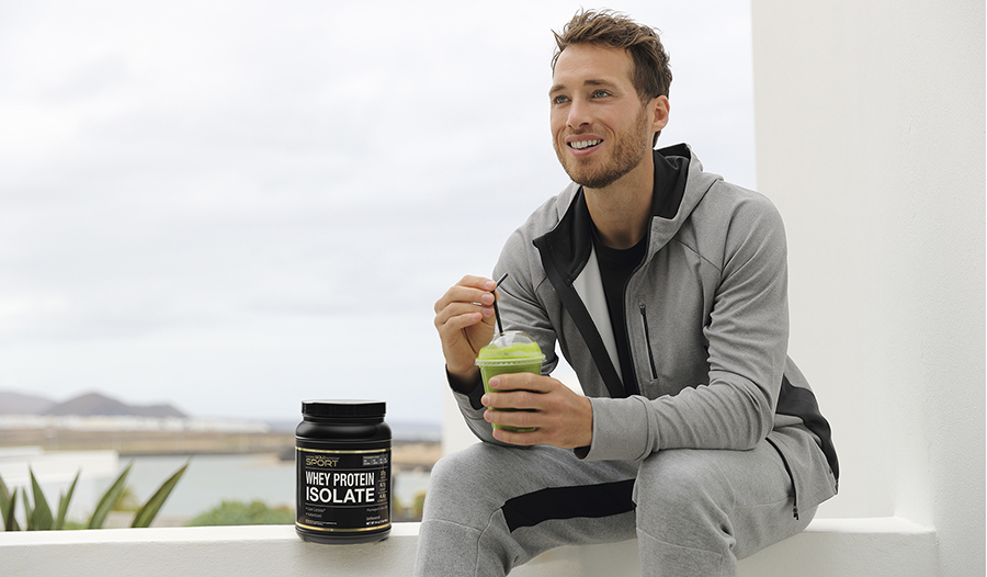 Athletic male drinking green smoothie outside