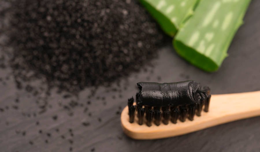Charcoal toothbrush and toothpaste on black table to charcoal and aloe