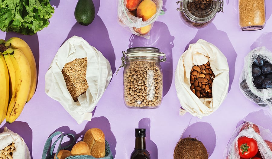 Healthy nuts, seeds, and grocery items on a purple background 