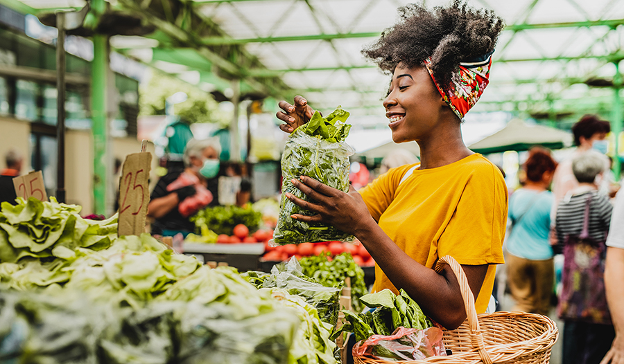 Healthy young black woman holding a basket full of groceries at the farmers market