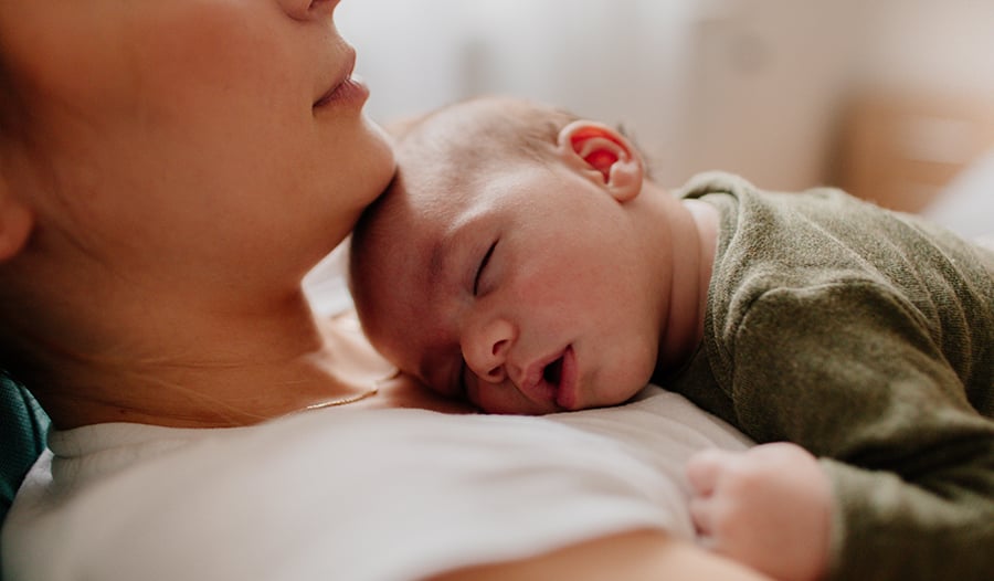 Newborn baby asleep on mother