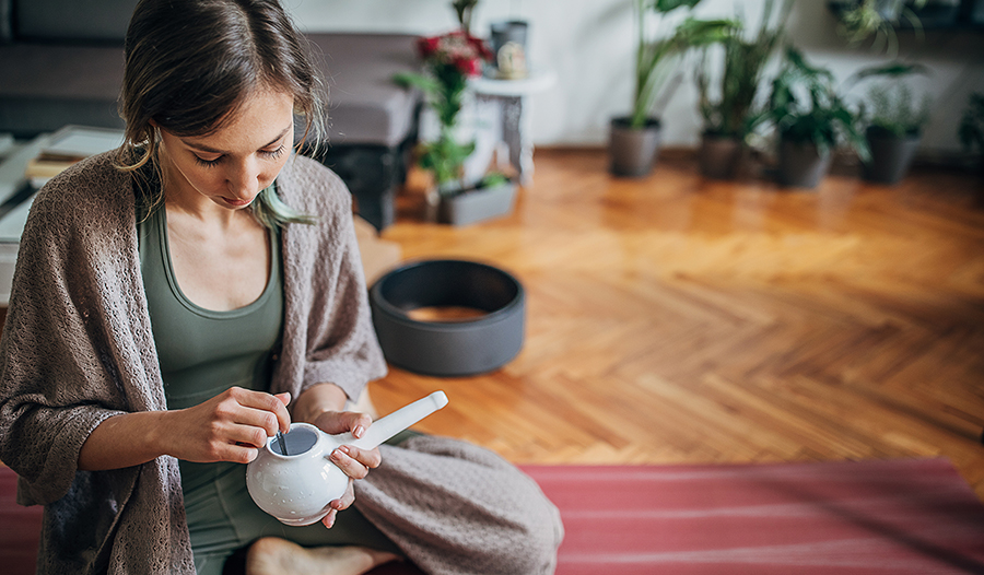 Young woman using neti pot at home after yoga practice