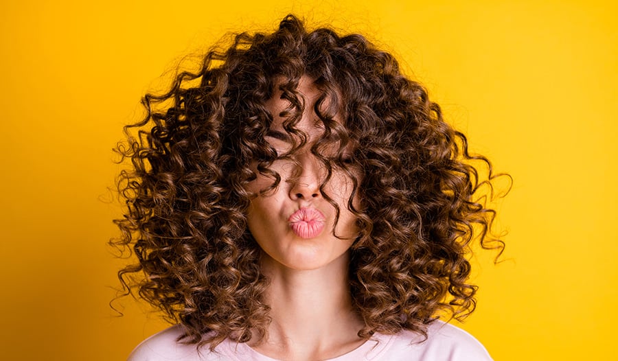 woman with natural curly hair over her face pouting at camera