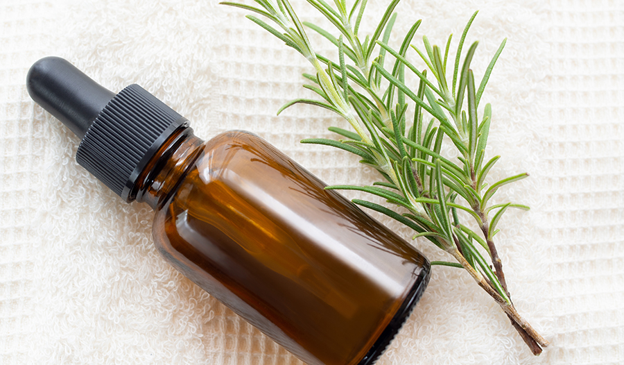 Rosemary oil on white towel with rosemary sprig