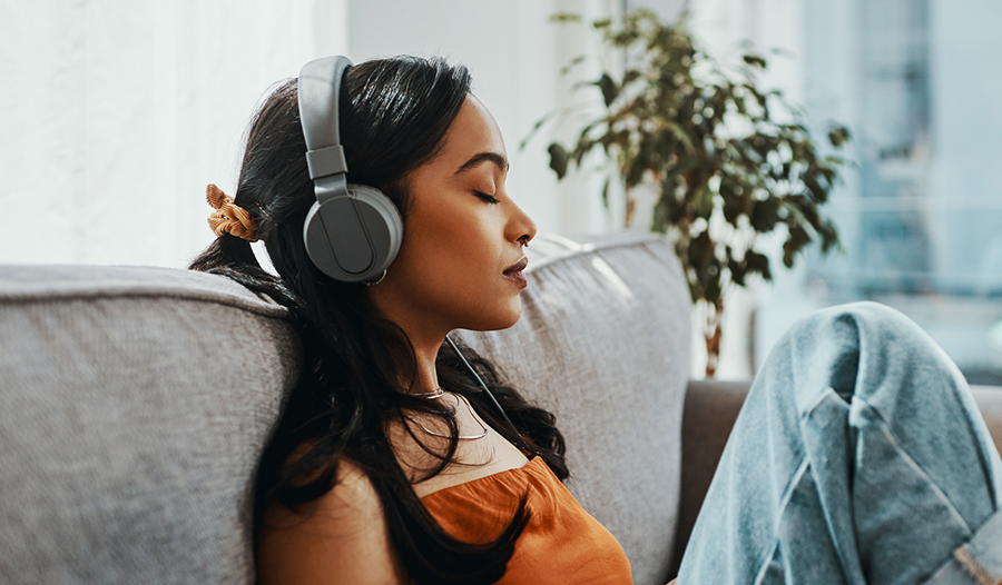 woman practicing self-care during pandemic by listening to music in headphones