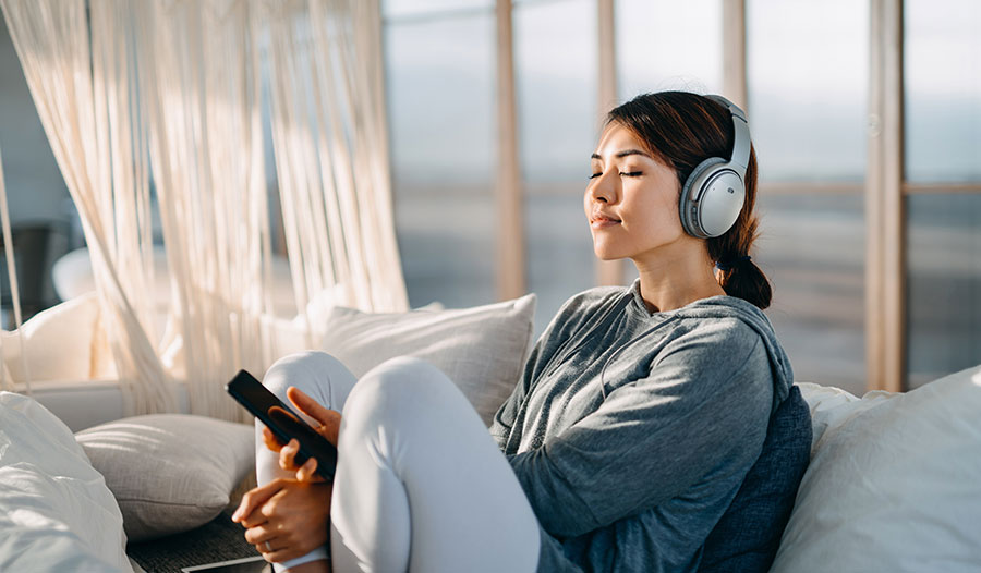 woman listening to music on her headphones while on her balcony