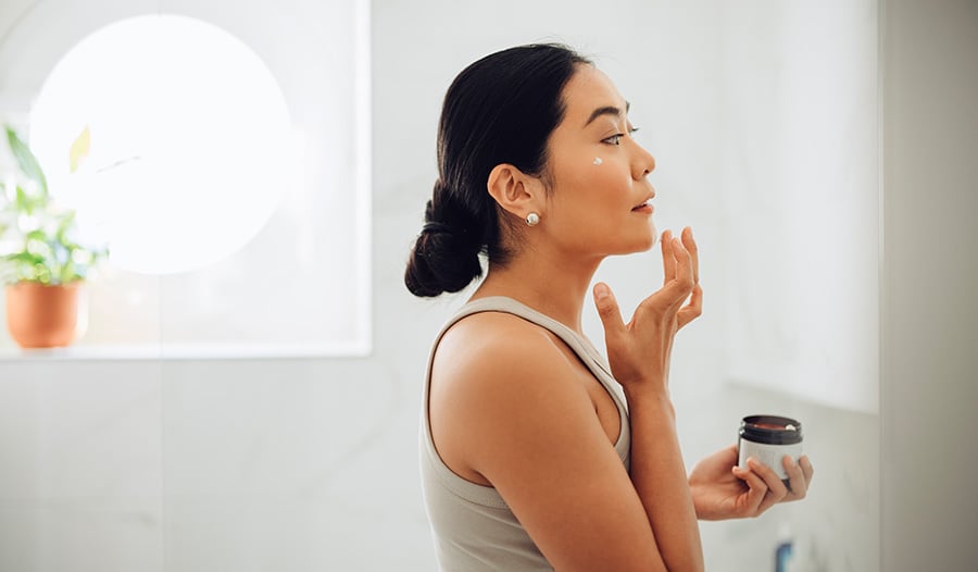 woman applying iHerb Brands skincare to her face