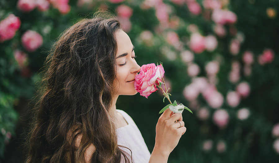 woman smelling a rose in a garden