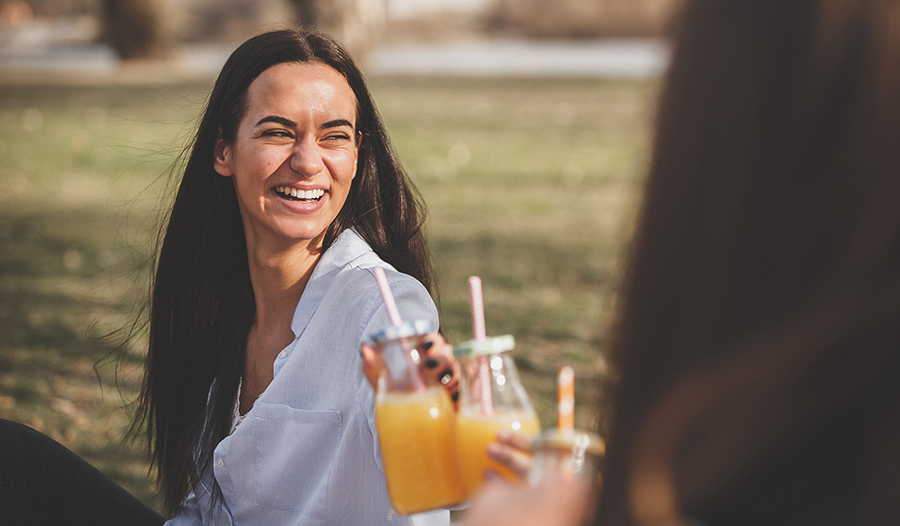 Young woman toasting with orange juice in the park