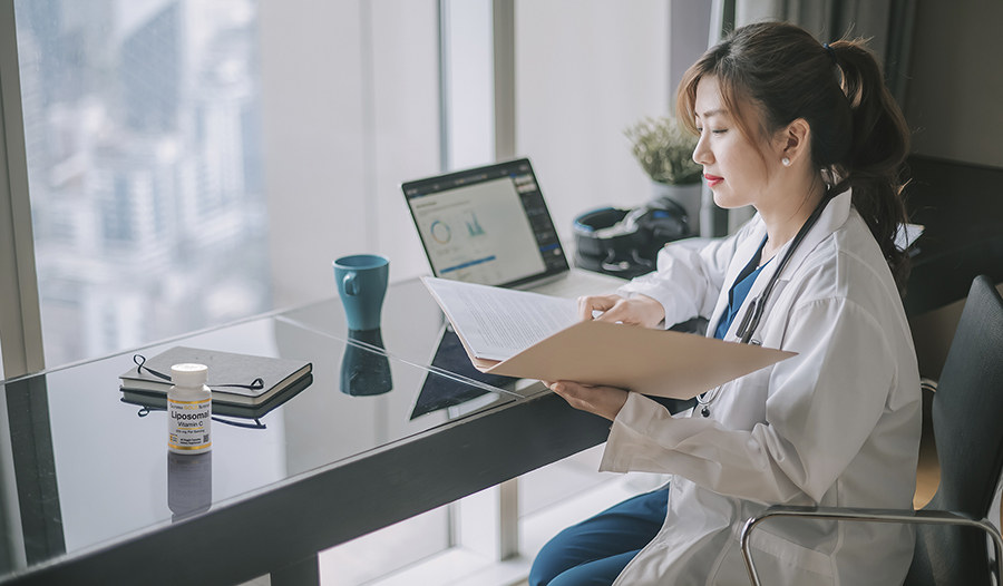 Asian woman in lab coat working and reviewing file at desk