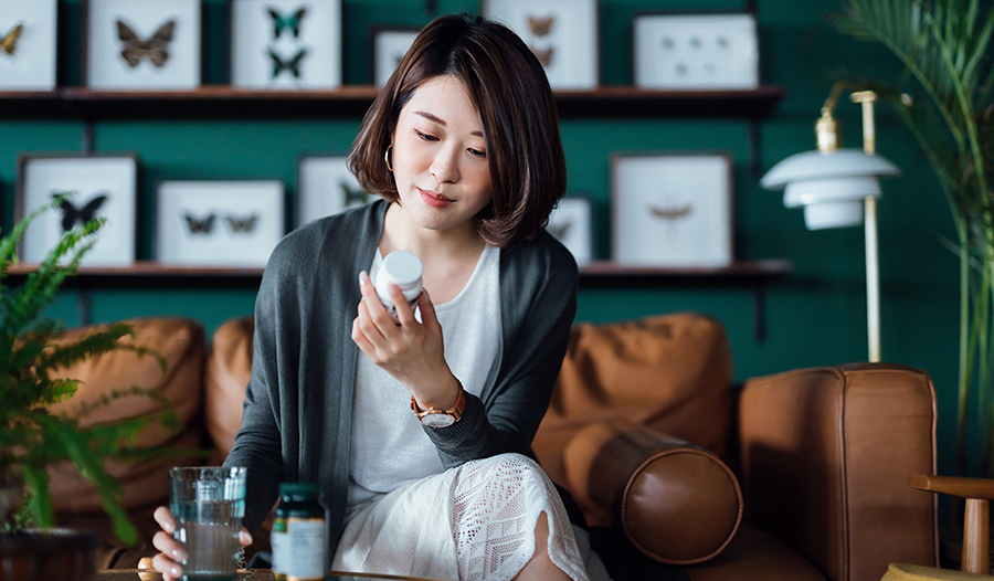 Woman looking at supplement label on bottle