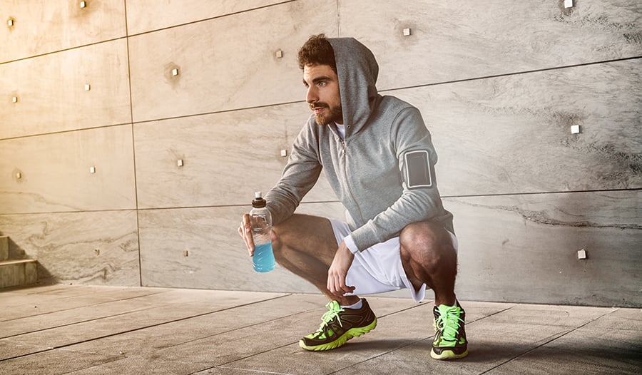 Athletic male taking a break from workout drinking sports drink