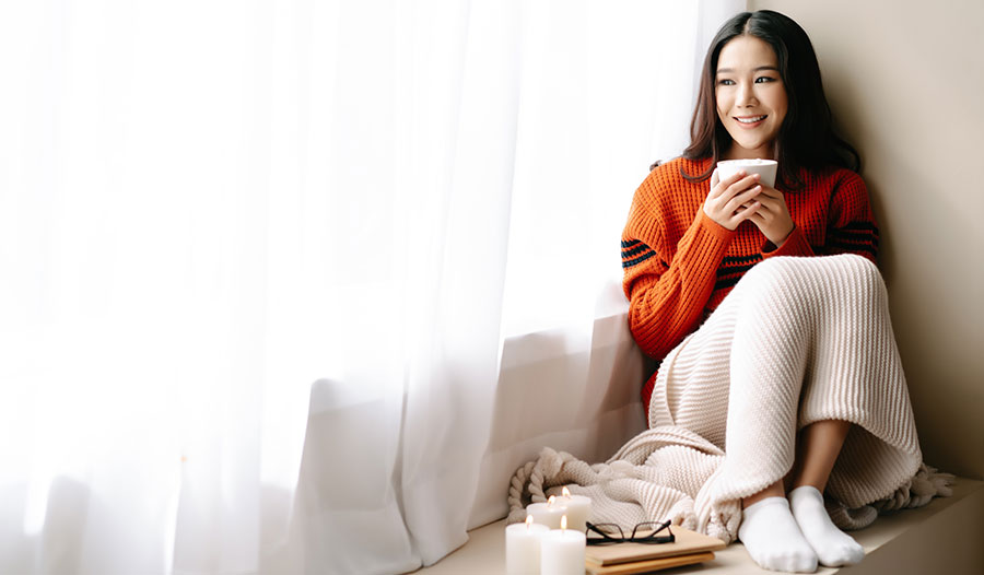 woman sitting on window ledge with a hot drink