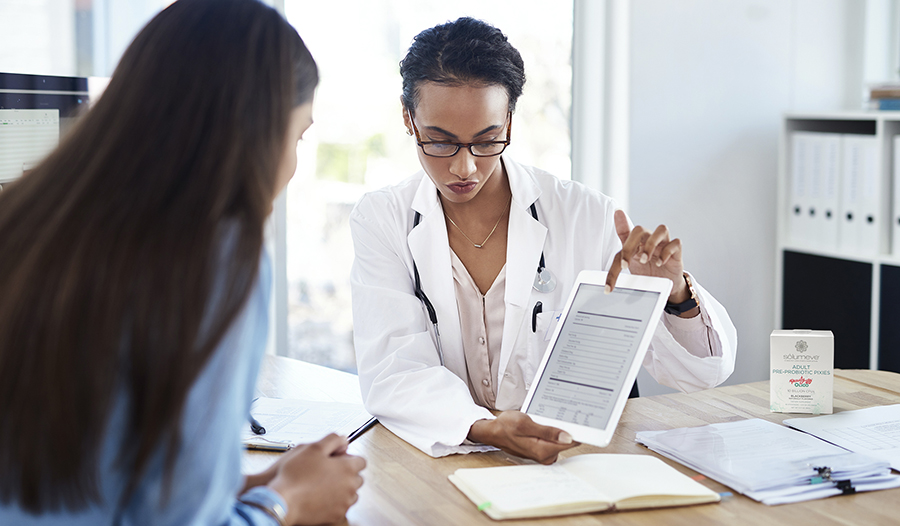 Doctor showing chart to patient in office with probiotics on table