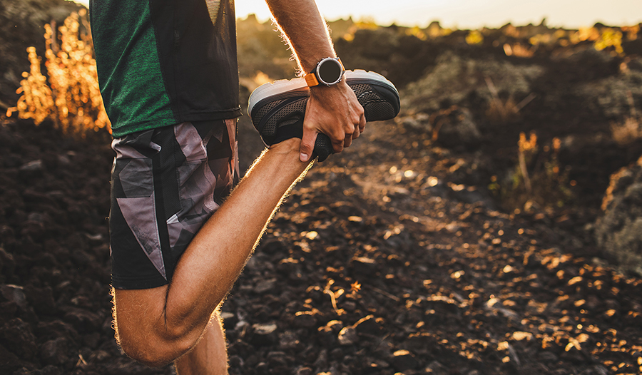 Male runner stretching leg preparing for run outdoors.