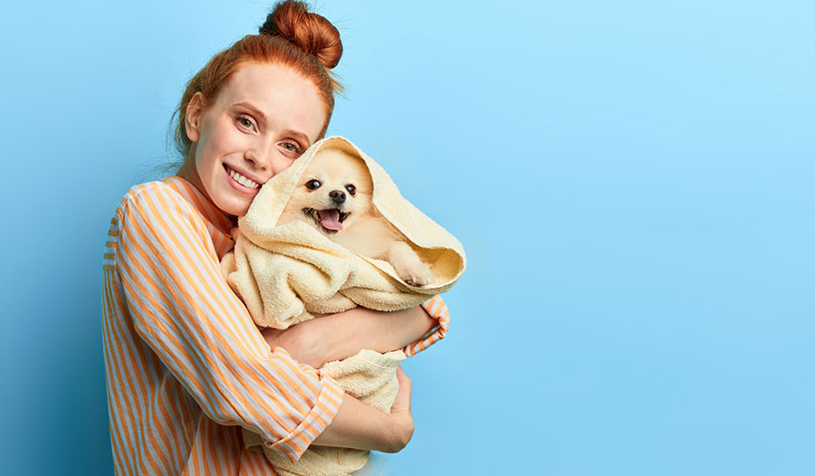 woman holding a puppy wrapped in a towel