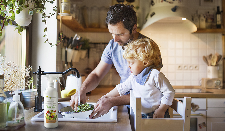 Dad washing vegetables in kitchen with son