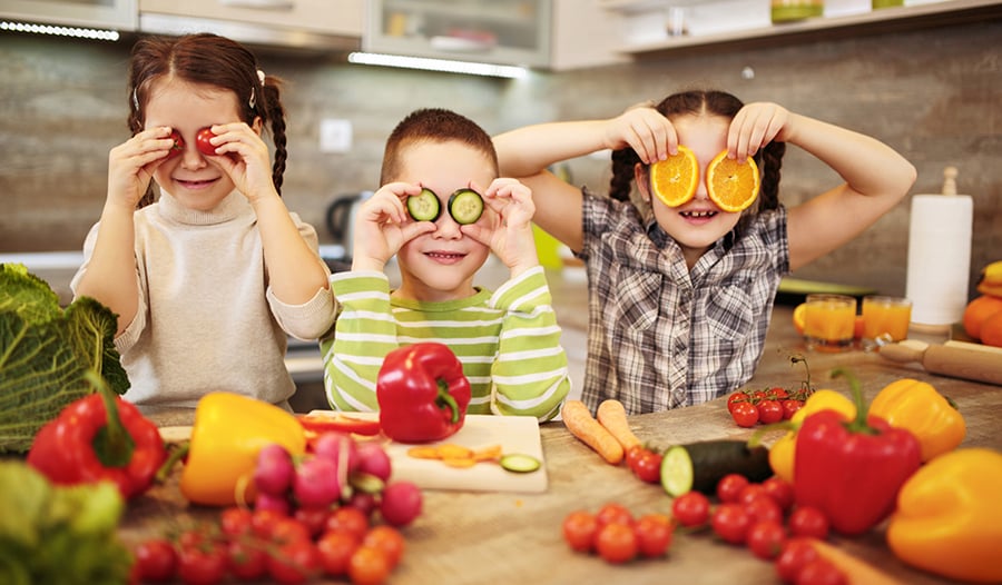 Healthy kids in the kitchen with fruits and vegetables