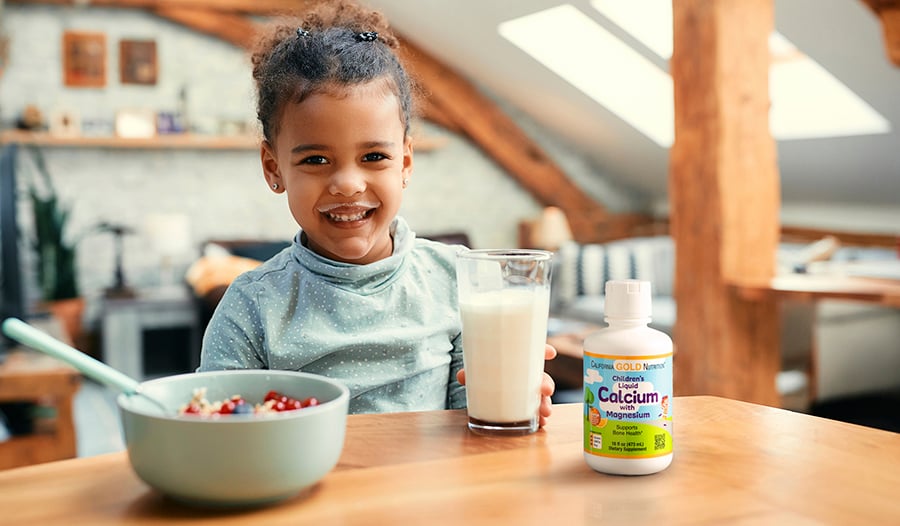 Young child drinking milk with cereal with children's calcium supplement on table