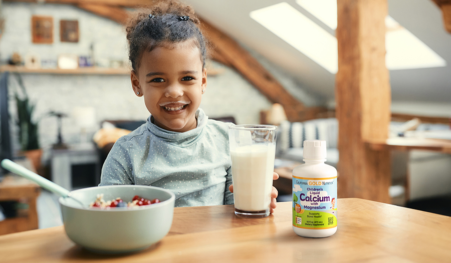 Young child drinking milk with cereal with children's calcium supplement on table